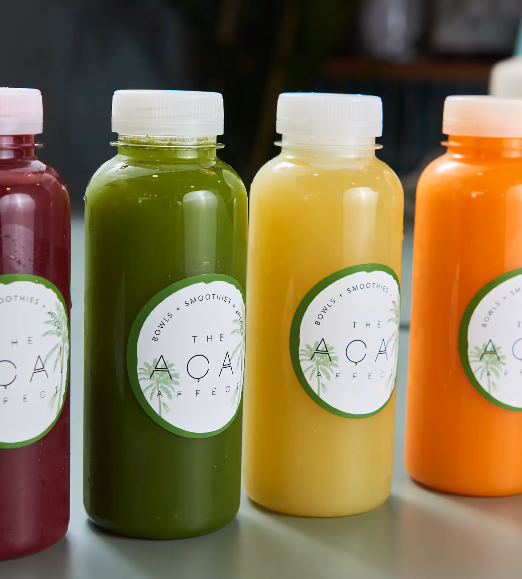 A row of colourful juices in The Acai Affect bottles