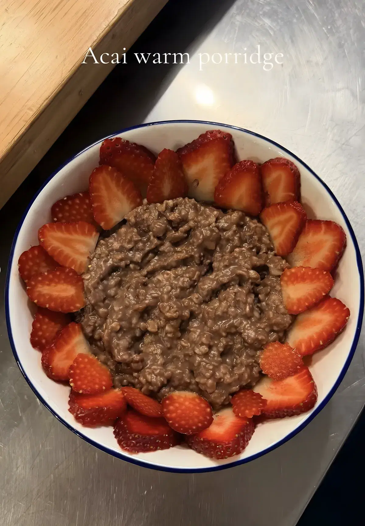 Acai warm porridge ringed with sliced strawberries