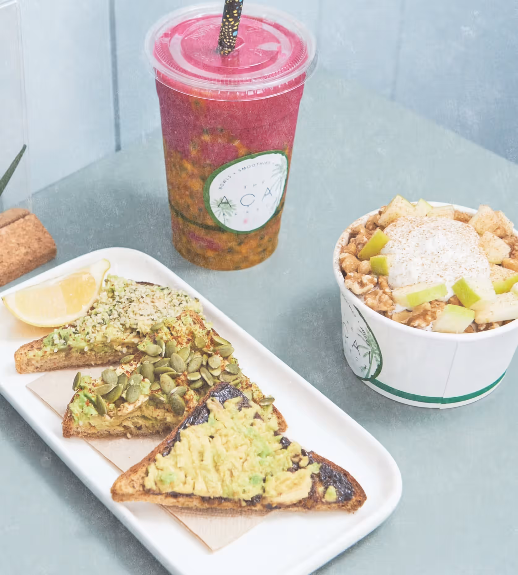 Smashed avocado toast, a layered smoothie and a bowl topped with apple and granola